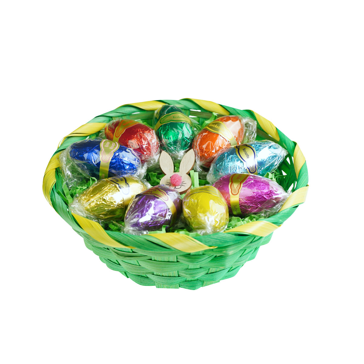Desserteier-9-Stueck-Korb Bunte, in Folie verpackte Schokoeier liegen in einem gruengelbem Korb, umgeben von gruenem Papier.