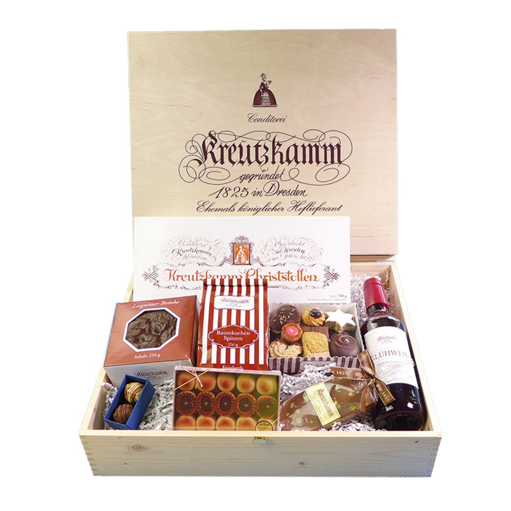 Weihnachtspaket-Nr4-Kiste Holzkiste mit verschiedenen Suessigkeiten, Flasche Gluehwein; umgeben von Verpackungen. Text: "Conditorei Kreutzkamm gegruendet 1825 in Dresden Ehemals koeniglicher Hoflieferant Kreutzkamm Christstollen".