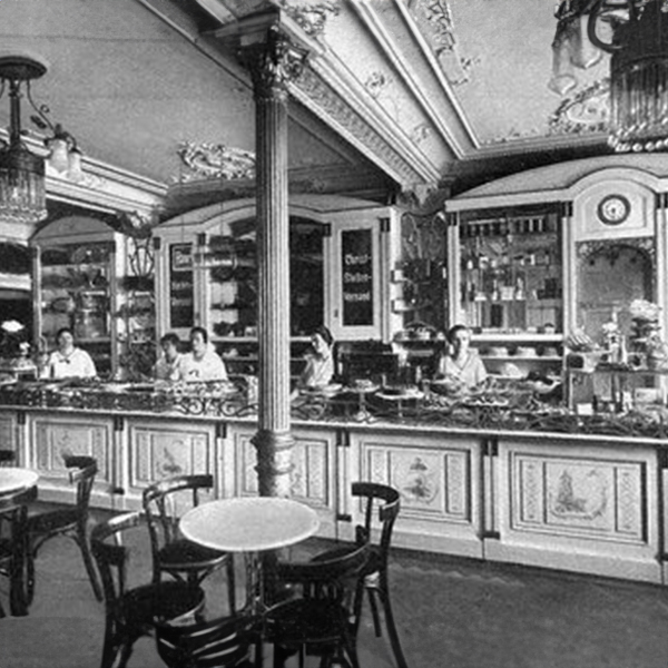 Vier Menschen arbeiten hinter einer stilvollen Theke in einem eleganten Cafe. Text: "Backhaus Kreutzkamm".