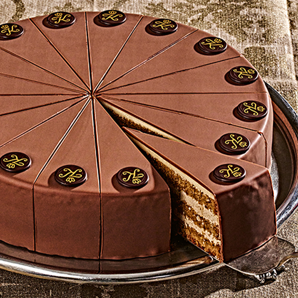 Schokoladentorte mit 16 Stuecken, verziert mit runden Schokoemblemen, ein Stueck auf Tortenheber.