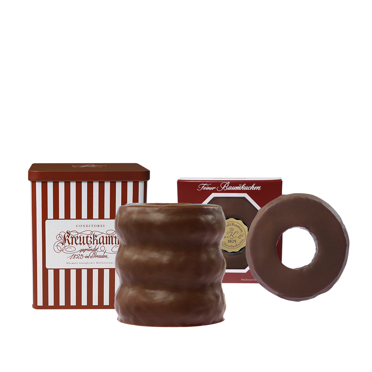 BK-Gruppe_Vollmilch2-rgb_2024-1 Schokoladenkuchen vor zwei rot-weissen Schachteln mit der Aufschrift "Kreutzkamm, Feiner Baumkuchen".