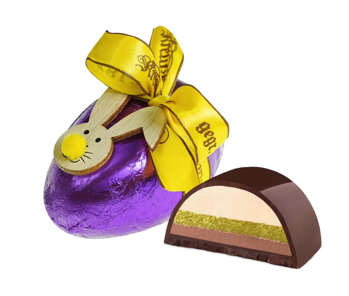 Lila-schokoladenei mit gelber Schleife und Hasenaufkleber; halbierte Praline daneben.