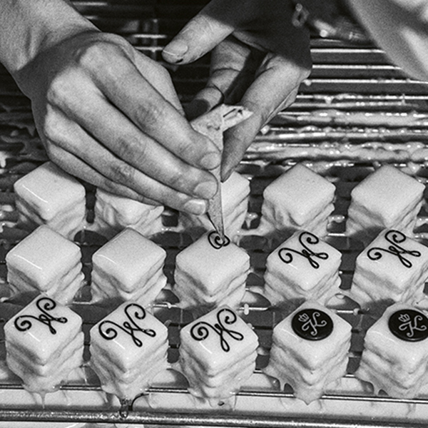 Haende verzieren kleine Gebaeckwuerfel auf einem Gitter mit Buchstaben und Symbolen.