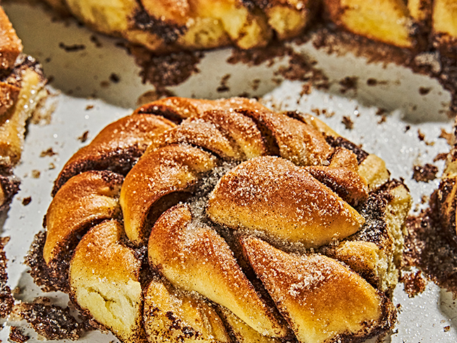Zimtschnecken liegen auf einem Backblech, frisch gebacken und mit Zucker bestreut.