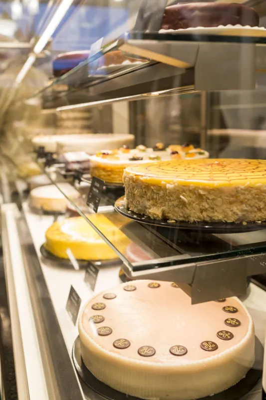 Kuchen in einer Vitrine; verschiedene Tortensorten; Hintergrund ist eine Baeckerei oder Konditorei.
