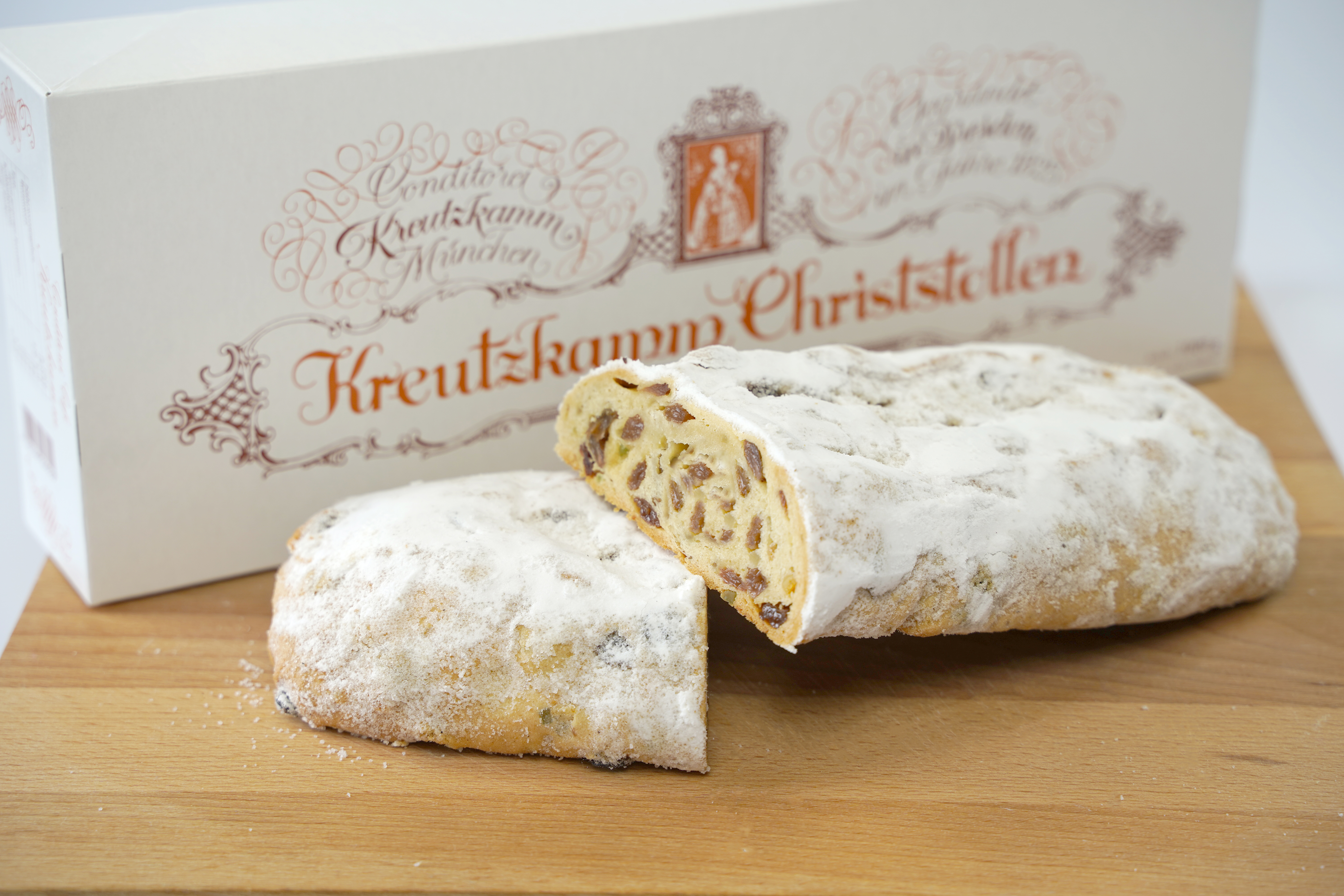 04-Rosinenstollen In der Verpackung von Backhaus Kreutzkamm Christstollen, steht auf einem Brett ein aufgeschnittener Christstollen.