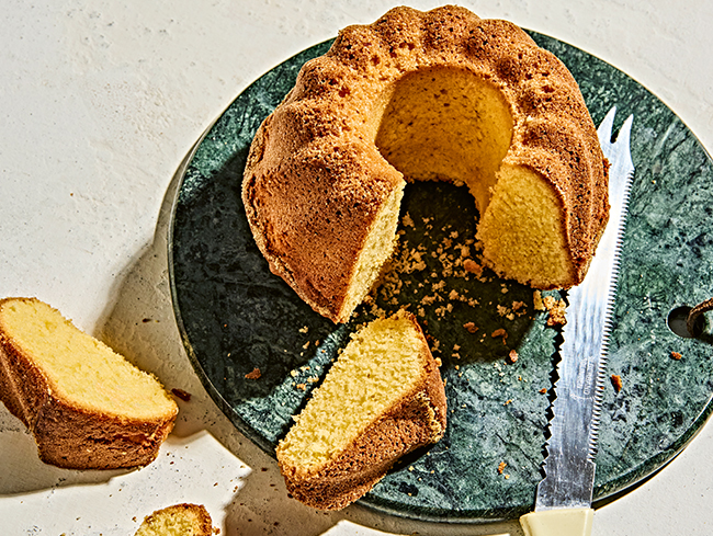 Ein Gugelhupf-Kuchen wird auf einem runden Brett geschnitten, Kr
